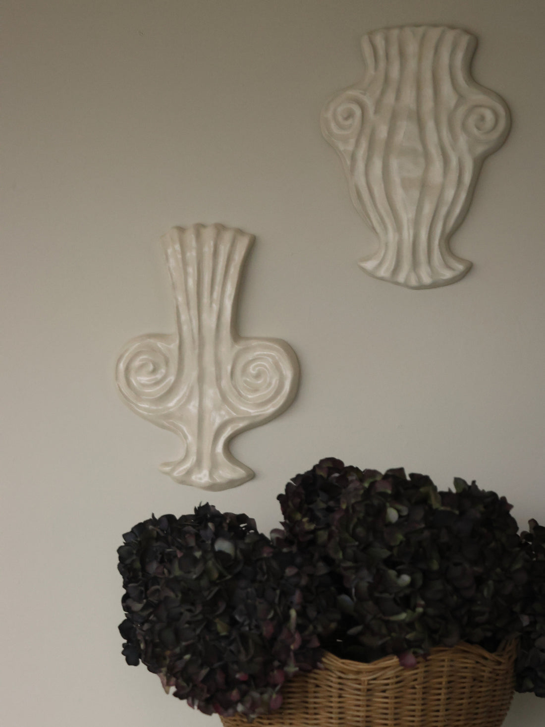 Thalia, ceramic muse vase relief in warm white glaze, shown alongside Euterpe muse vase,both mounted on a wall